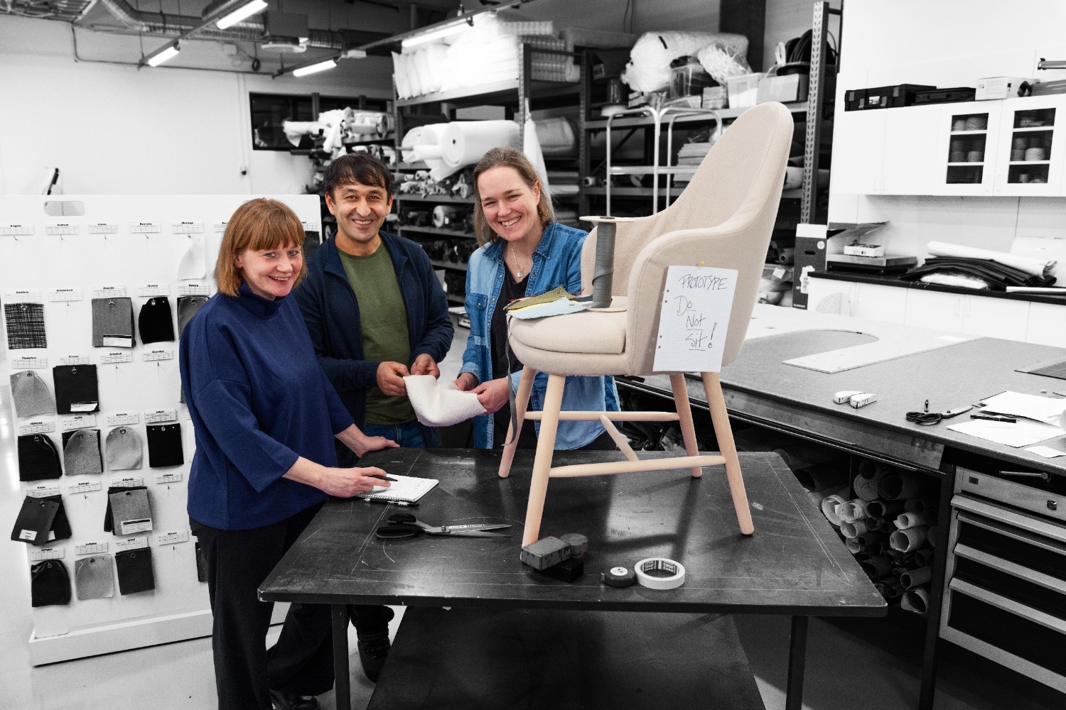 Collaborative furniture design process with team members and a chair prototype.